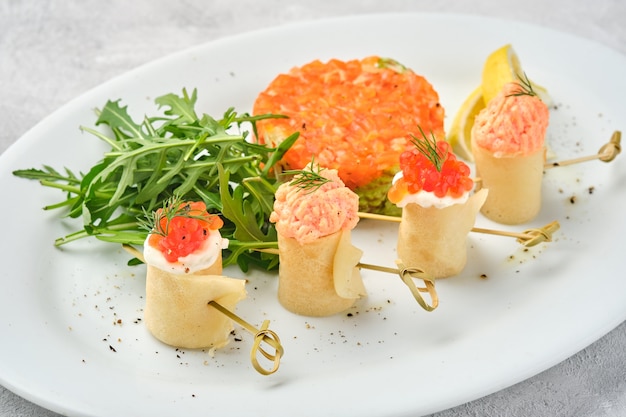 Thin rolled pancakes, crepes with salmon and red caviar, and fish tartare