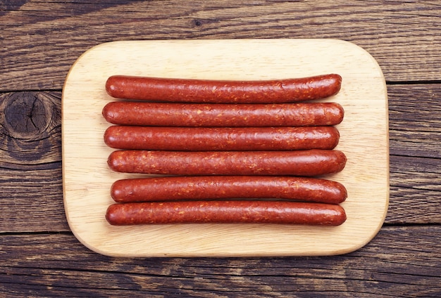 Thin smoked sausage on wooden table