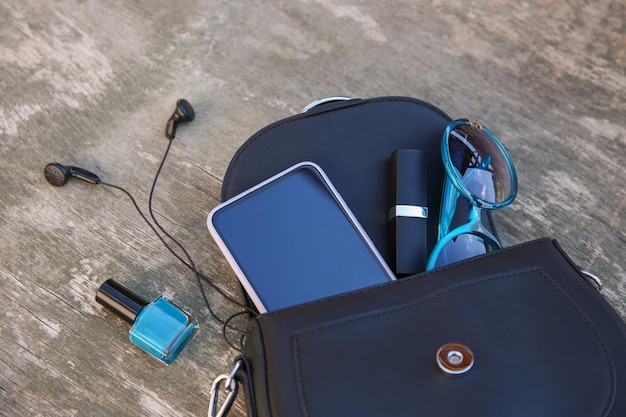 Foto cose dalla borsa aperta della signora. i cosmetici e gli accessori da donna sono caduti dalla borsa blu.