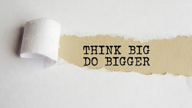 Think big do bigger. words. text on grey paper on torn paper background