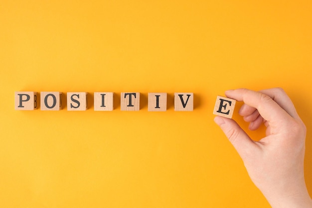 Think positively concept. Close up pov flatlay view photo of female hand putting last letter in word positive in a line isolated vivid color backdrop