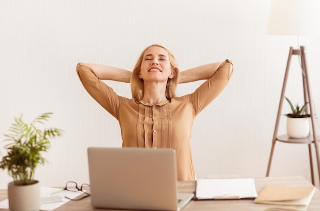 thinking about vacation woman having break at work holding arms behind head