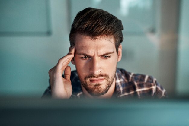 Thinking about what to do next Shot of a young businessman experiencing a headache at the office