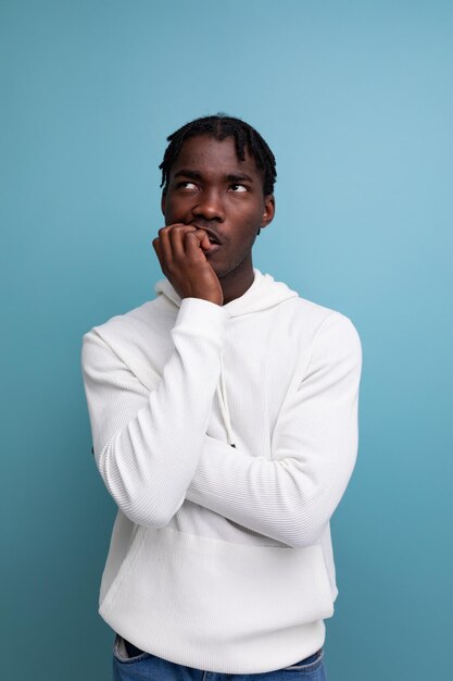 Thinking african young brunette man looking at ceiling on studio isolated background