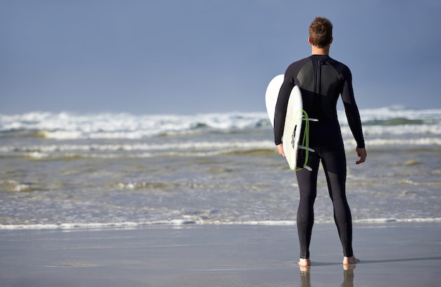 사진 해변을 생각하고 서핑 보드를 가진 남자의 등 해변에서 휴가 주말과 휴가에 파도를 서핑하기 위해 자연과 사람이 바다를 여행하여 물 스포츠 모험과 호주에서 여름