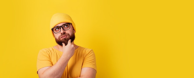 Thinking bearded man looking up over yellow background panoramic layout