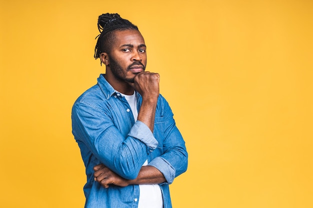 Photo thinking black african american man with serious expression looking, posing isolated over yellow background.