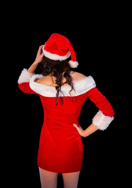 Photo thinking brunette in santa outfit posing with hand on hip