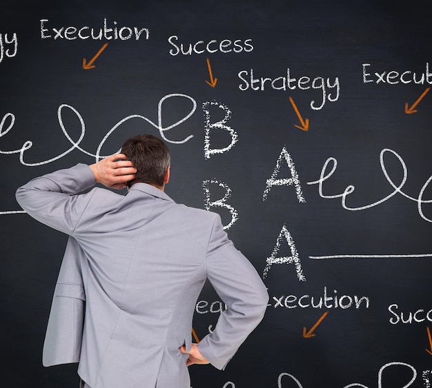 Thinking businessman against blackboard with business buzzwords