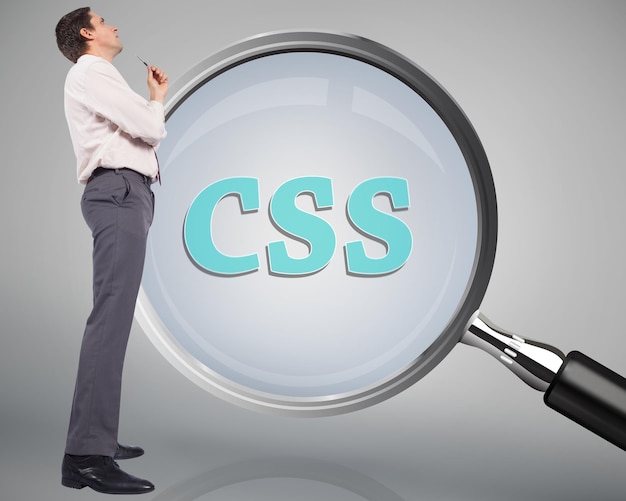 Thinking businessman holding pen against magnifying glass showing css word