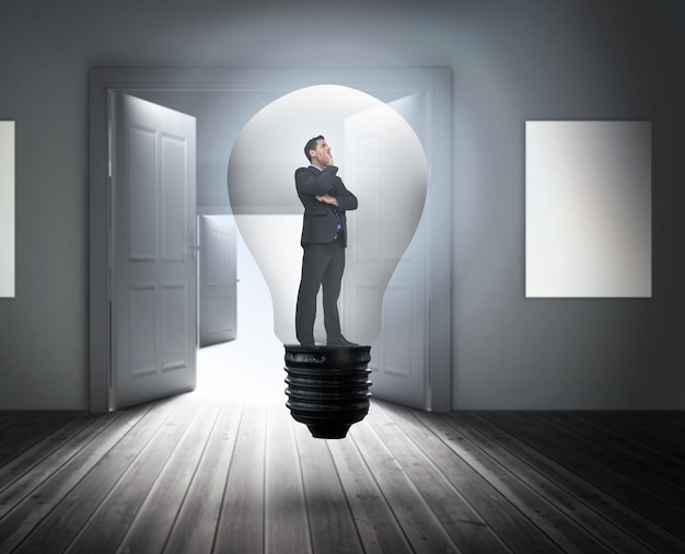 Фото Думающий бизнесмен в лампочке против дверей, освещающих яркий свет