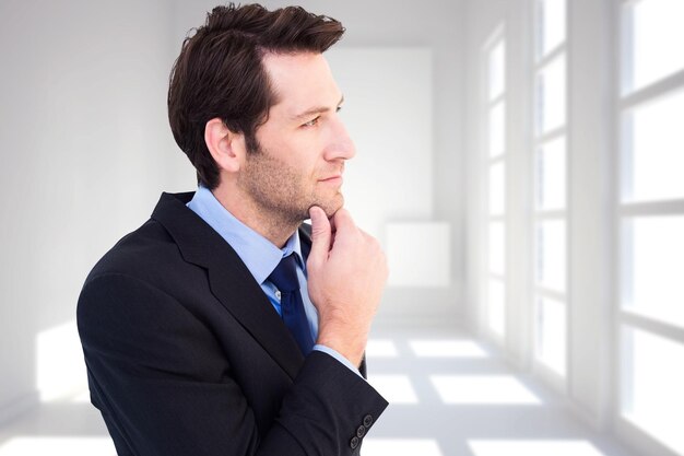 Photo thinking businessman touching his chin against white room with squares at wall