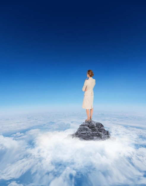 Photo thinking businesswoman against mountain peak through the clouds