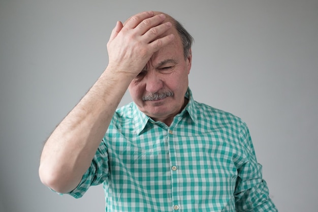 Thinking caucasian senior man holding hands on head