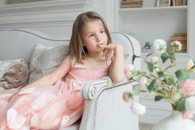 Thinking child girl in pink dress at home