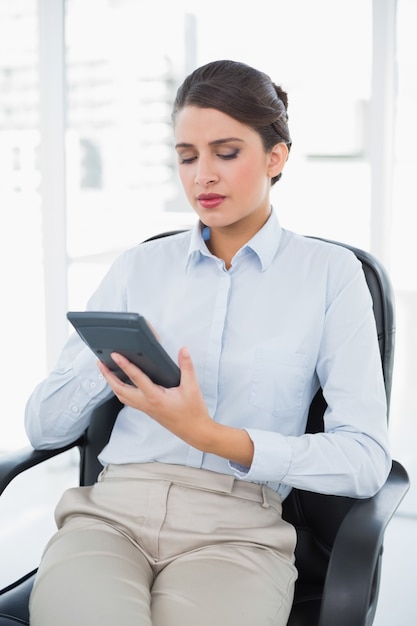 Thinking classy brown haired businesswoman using a calculator