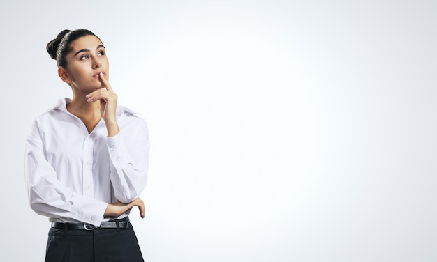 Thinking concept with pensive girl in white shirt on abstract white background with place for your text or logo mockup