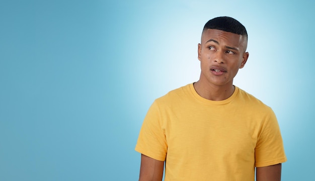 Thinking confused or problem solving and a man on a blue background in studio with a question on mockup doubt idea or why with a young person on space for planning or brainstorming a solution