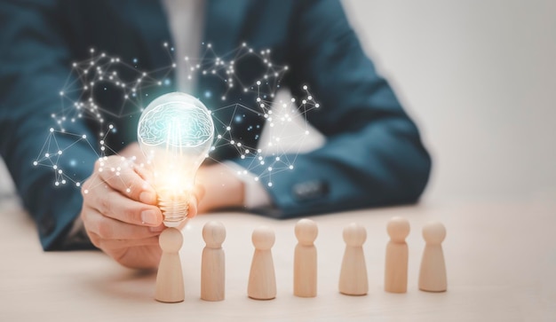 Thinking and creative Businessman hand holding light bulb on the wooden people Teamwork and idea concept Successful team leader Businessman hand choose people standing out from the crowd