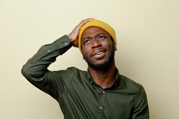 Thinking grabbed head young african american male in hat wearing green shirt isoloated on white background