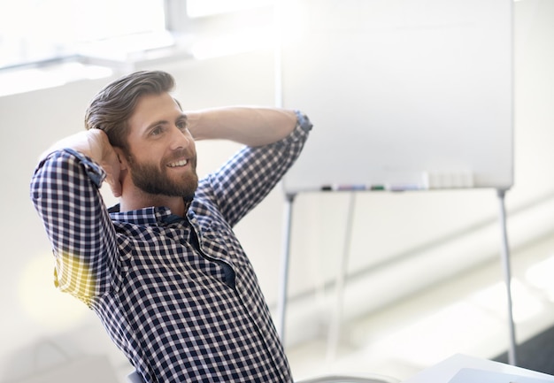 Thinking of his countless successes Shot of handsome young man relaxing with his hands behind his head in an office