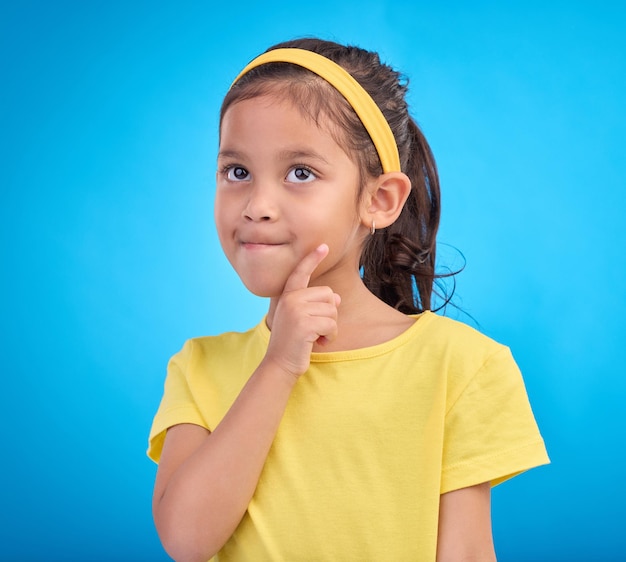 Thinking idea and face of child in studio with contemplation thoughtful and planning expression Ideas mockup innovation and young girl on blue background for brainstorming question and curious