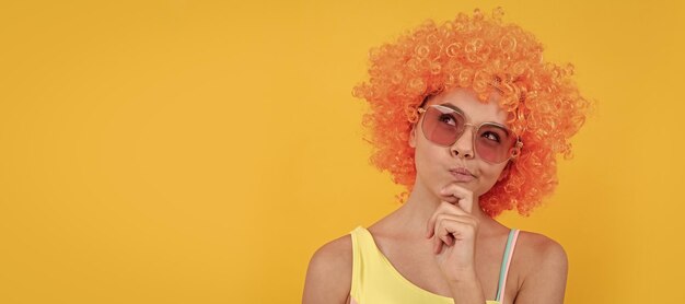 Thinking kid in curly clown wig having fun thoughtful child wear sunglasses and swimsuit funny