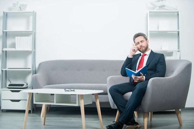 Thinking mature businessman in suit sit in office with planner