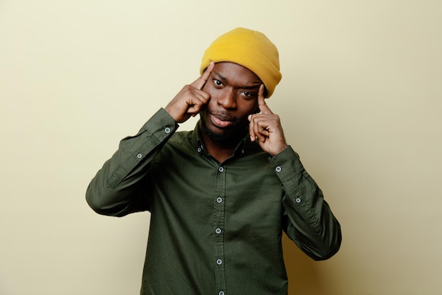 Thinking putting fingers on head young african american male in hat wearing green shirt isoloated on white background