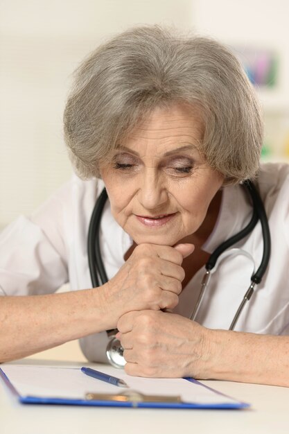 Thinking senior doctor woman sitting at table