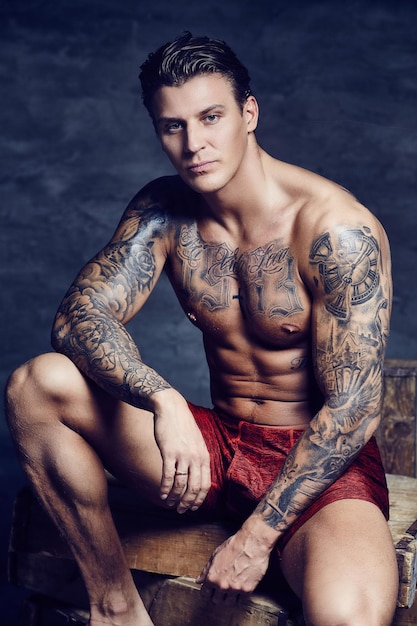 Thinking shirtless muscular man with tattooes on his body.