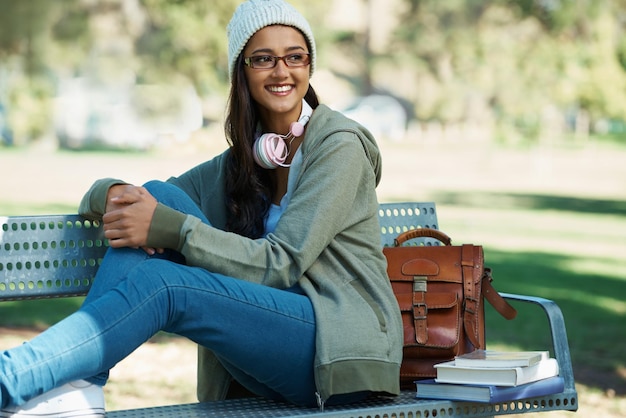 Photo thinking student and woman in park with books for studying learning and reading outdoors education happy and person with bag textbooks and headphones relax on bench for university or college