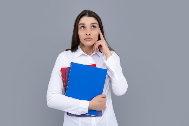 Thinking student young student girl in casual clothes isolated\
on gray background studio portrait hold notebooks cheerful young\
attractive student woman