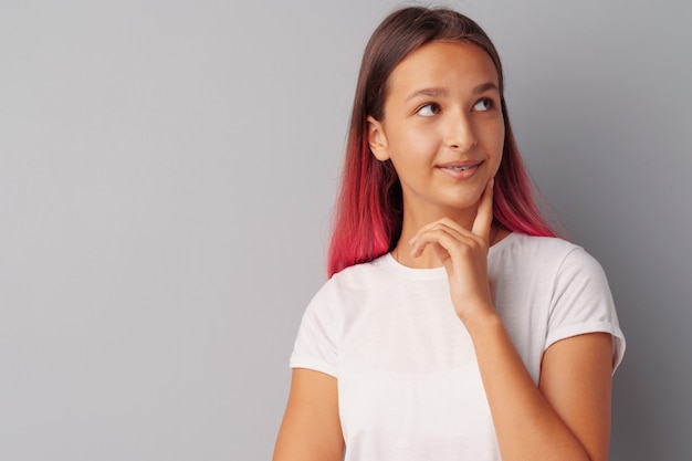 thinking teen girl standing over a gray background