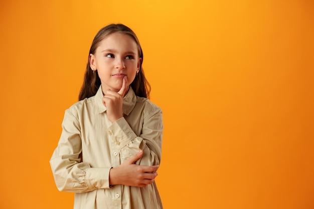 Photo thinking teen girl in studio over yellow background