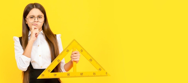 Foto una ragazza adolescente pensante in uniforme e occhiali tiene il triangolo matematico per misurare la misurazione banner di studentessa ritratto di un allievo del bambino della scuola con spazio per la copia