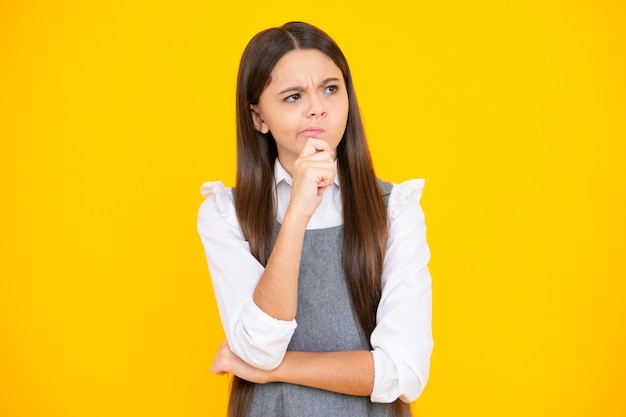 Thinking teenager girl thoughtful emotion thoughtful teenager girl touch chin and thinking pensive child making idea posing isolated on yellow isolated background