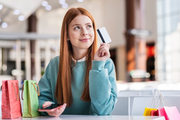 Thinking woman holding a credit card