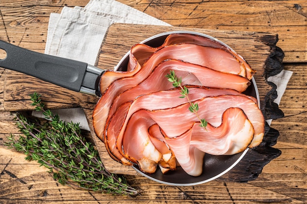 Thinly sliced German Black Forest Ham bacon in skillet Wooden background Top view