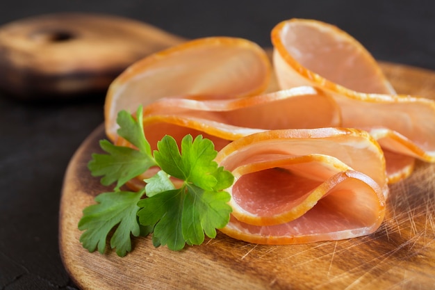 Prosciutto affumicato a fette sottili su una tavola. spuntino di carne