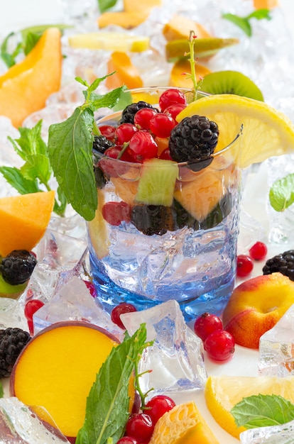 Thirst quenching glass with cold water and fresh summer fruit with ice