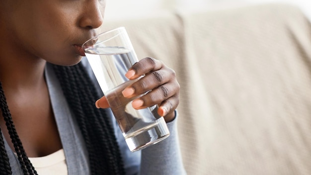thirsty black girl drinking clean water from glass at home