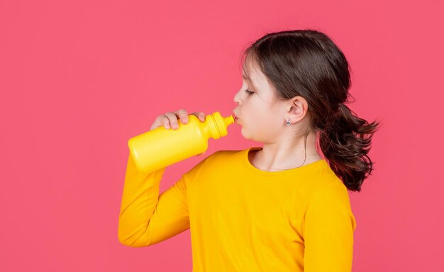 Thirsty kid drinking water on pink background