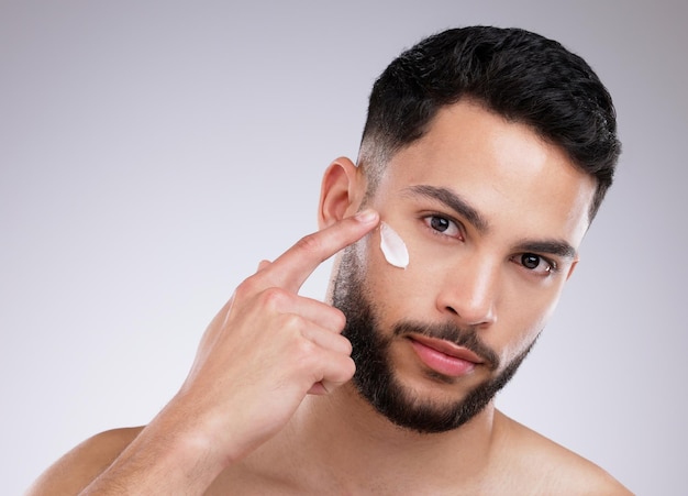 This face cream deeply moisturises Shot of a handsome young man applying moisturiser on his face against a studio background