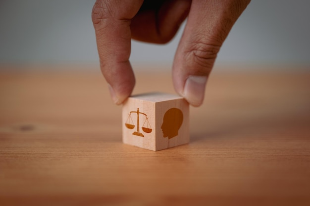 Photo this image reflects the concept of business ethics with a hand flipping wooden cubes displaying symbols of ethics inside a head representing the importance of ethical decisionmaking in business