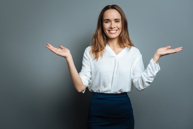 This is balance. Cheerful nice young woman smiling and looking at you while holding her hands up