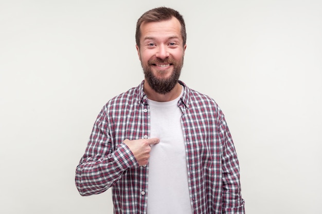 This is me. Portrait of pleased happy man with beard in casual plaid shirt smiling and pointing at himself, boasting achievements, saying I did it. indoor studio shot isolated on white background