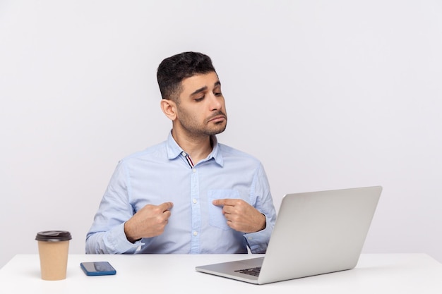 This is me. Selfish businessman sitting office workplace, pointing himself and looking self-confident arrogant at laptop screen, talking on video call and boasting. indoor studio shot isolated