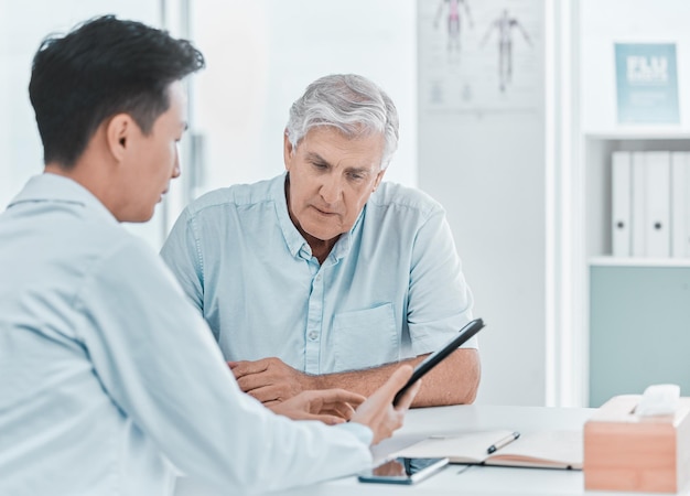 Photo this is what your blood tests showed shot of a mature man sitting with his doctor and going over his medical results on a digital tablet in the clinic