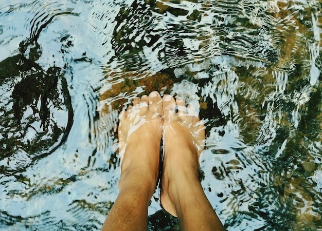 Foto questa foto mostra una persona che immerge i piedi in acqua molto limpida